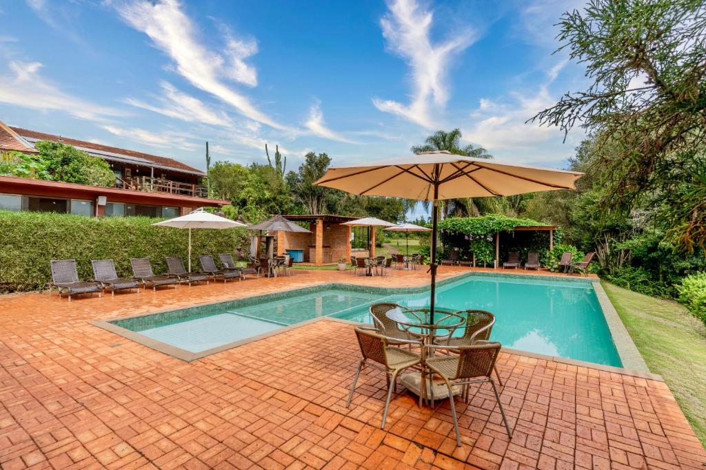 a swimming pool with a table and an umbrella at Hotel Fazenda Vale Alvorada in Toledo