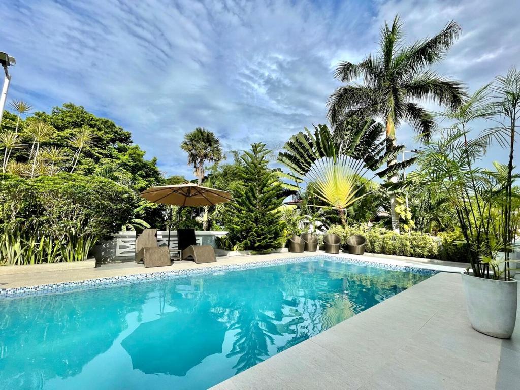a swimming pool with an umbrella and palm trees at private villa with private pool in Aborlan