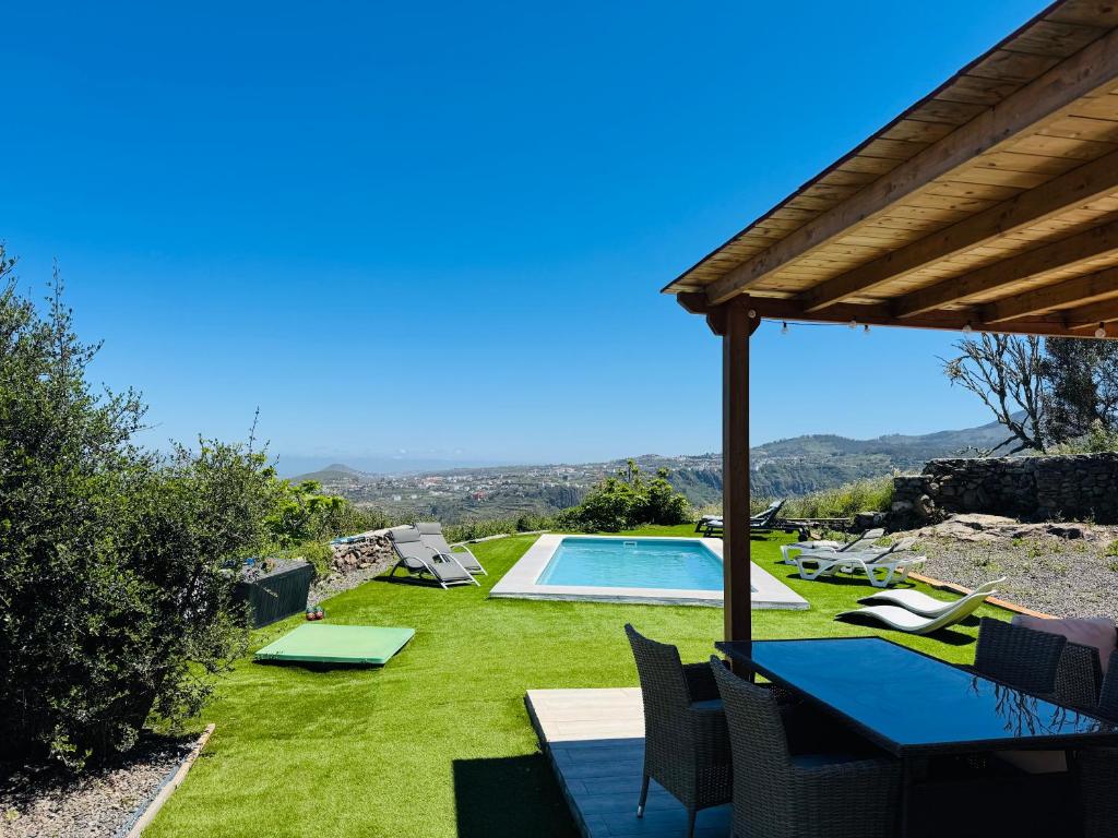 a patio with a table and chairs and a swimming pool at Villa Alegría Gran Canaria Piscina Climatizada in Las Palmas de Gran Canaria
