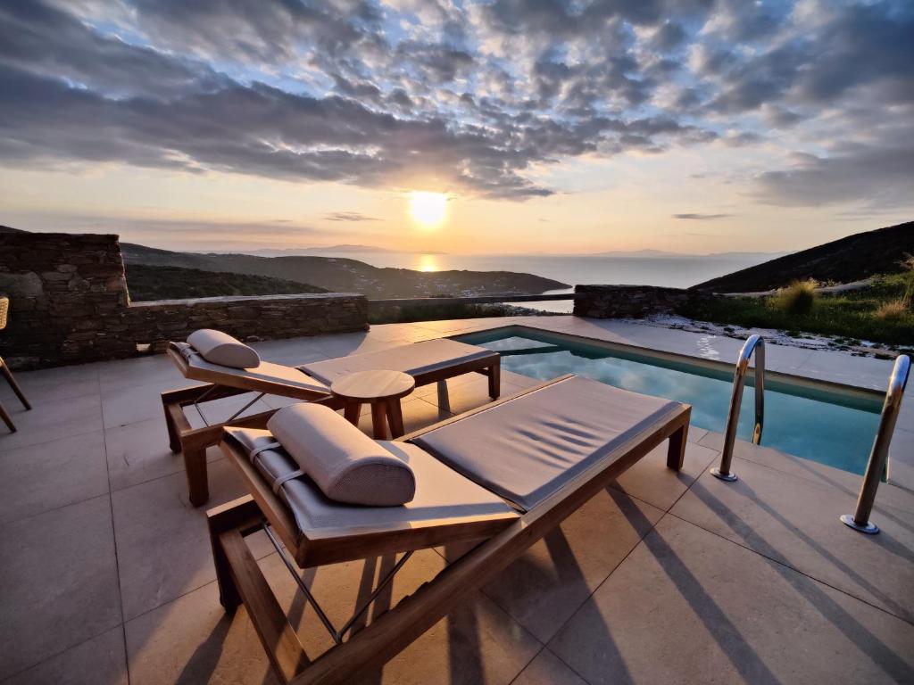a villa with a swimming pool and a sunset at Refoulia Eco Suites in Vathi