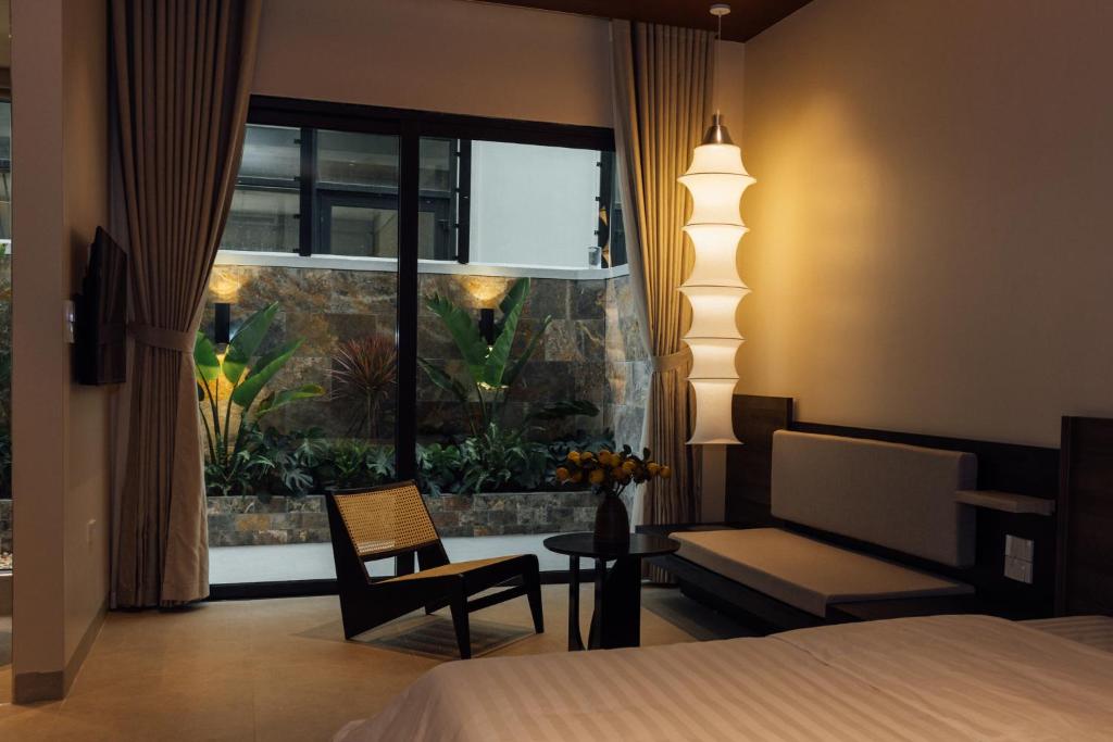 a bedroom with a bed and a chair and a window at Lavena Boutique Hotel in Sầm Sơn