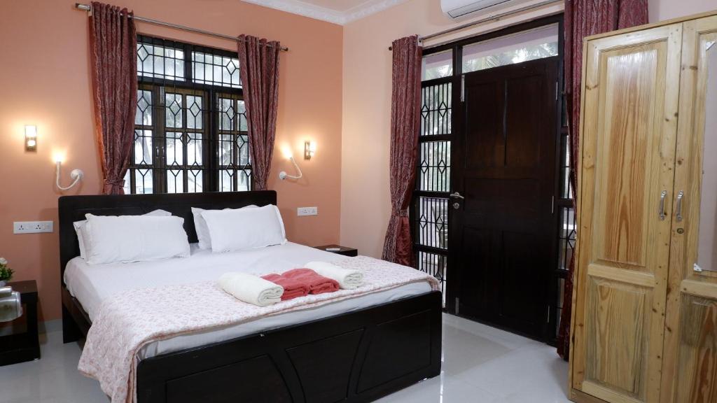 a bedroom with a bed with a black door and windows at Jasmine Guest House in Majorda