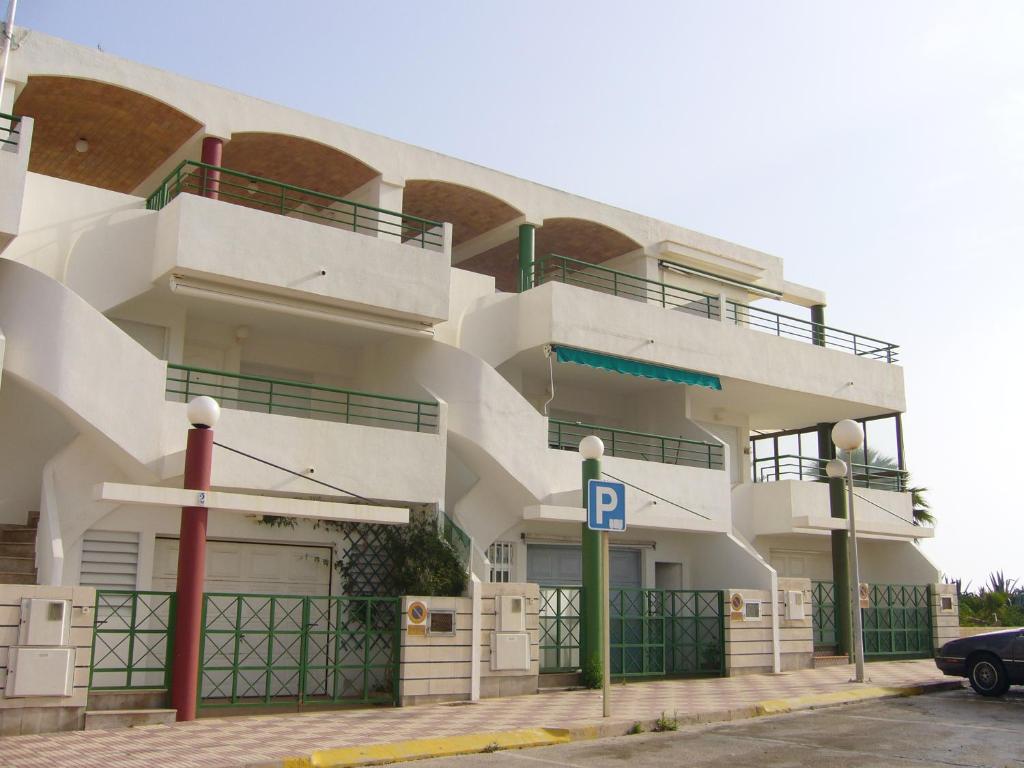 a large white building with a parking lot at Planta baja junto al mar con barbacoa in El Brosquil