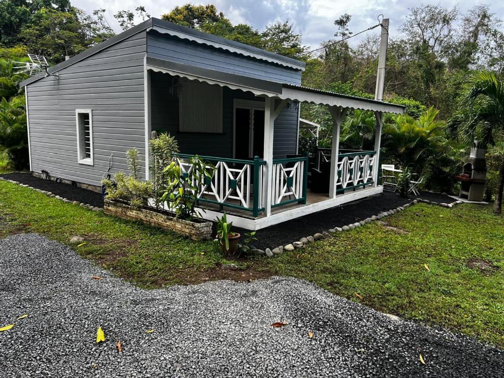 a small gray house with a porch on a yard at Ti ÉMERAUDE in Pointe-Noire
