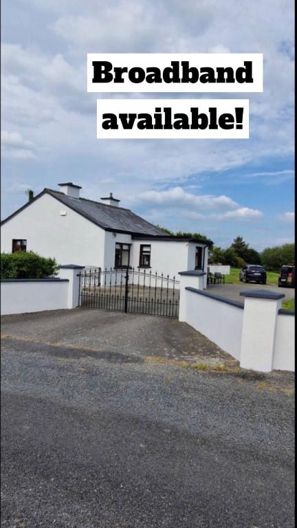 a white house with a fence in front of it at Bridie's Cottage in Mullagh