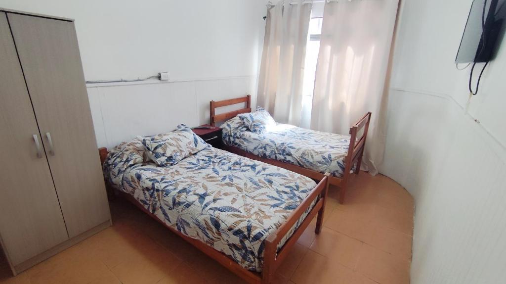 two beds in a small room with a window at Hostal Verona in Antofagasta