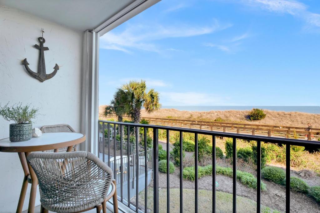 a balcony with a table and chairs and a view of the ocean at Seawind Sanctuary in Carolina Beach