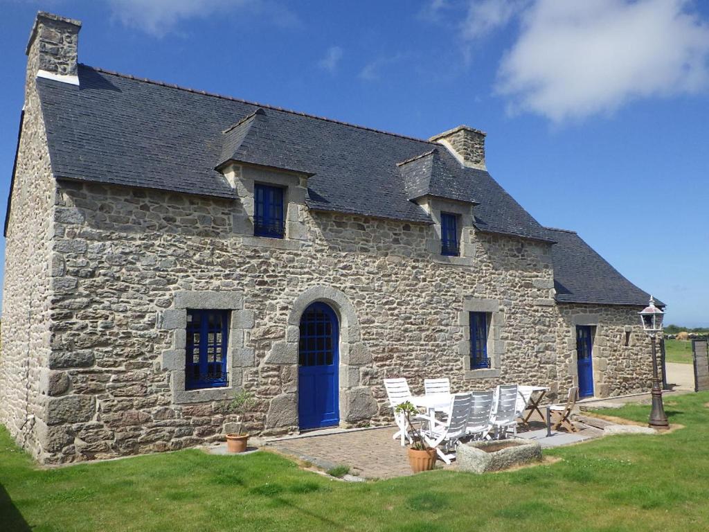 a stone house with two white chairs in front of it at Gites laurent in Guissény