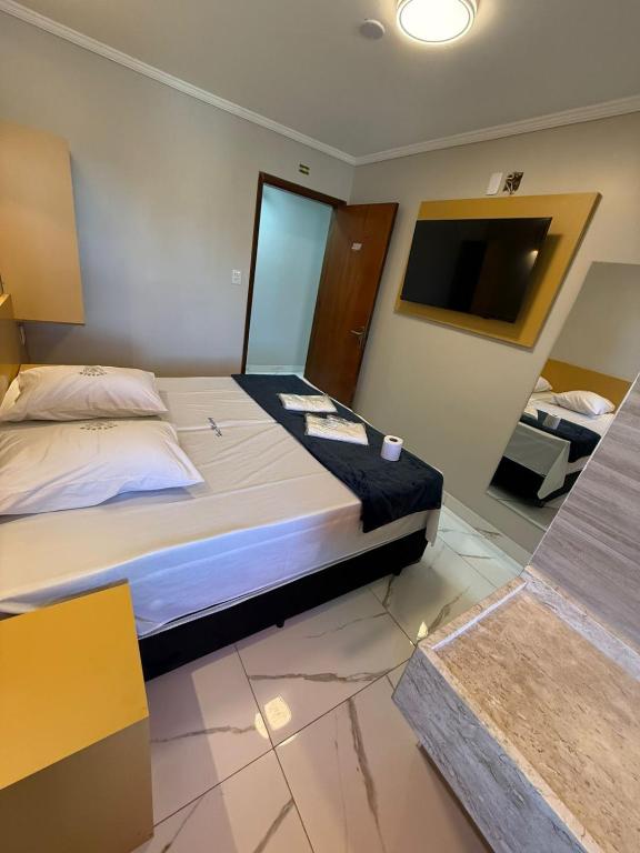 a bedroom with a large bed and a flat screen tv at Hotel Mustang in São Paulo