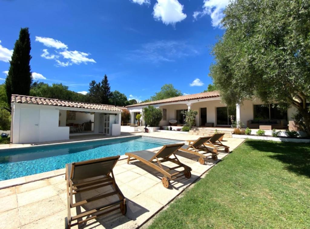 a swimming pool with chairs and a house at Pomme Reinette in Le Val