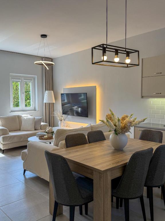 a dining room and living room with a table and chairs at Lūm Posidonia in Posidhonía