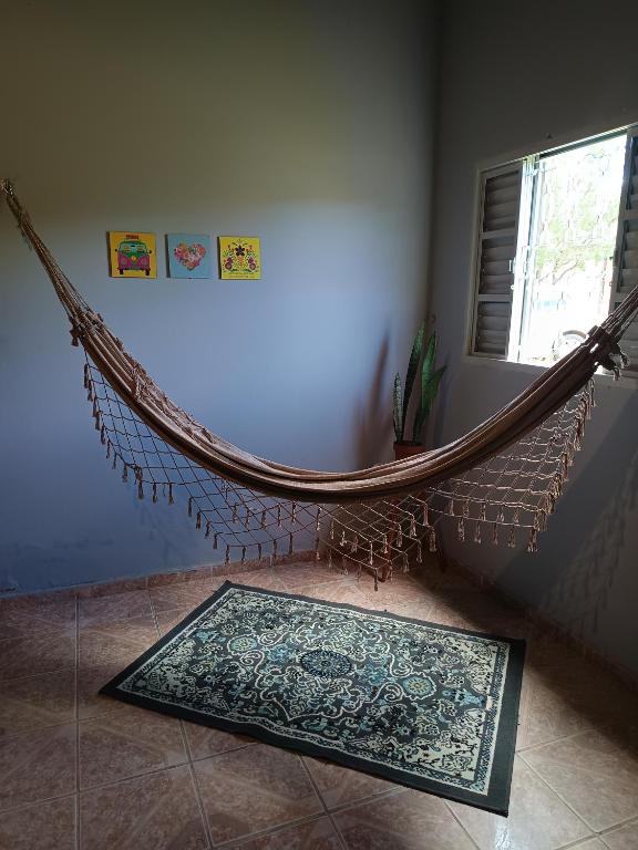 a hammock in the corner of a room with a rug at Hostel do Cerrado in Cavalcante