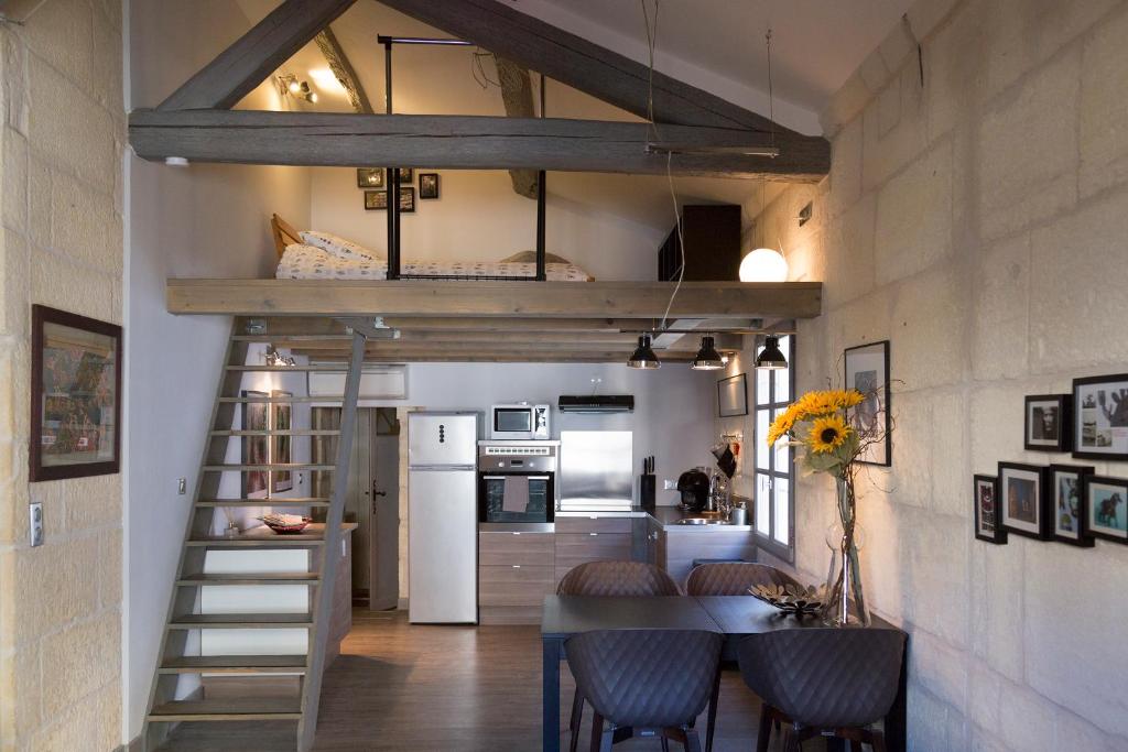 Cette chambre comprend une mezzanine et une cuisine avec une table. dans l'établissement Appartements "La Chambre D'Ami", à Arles