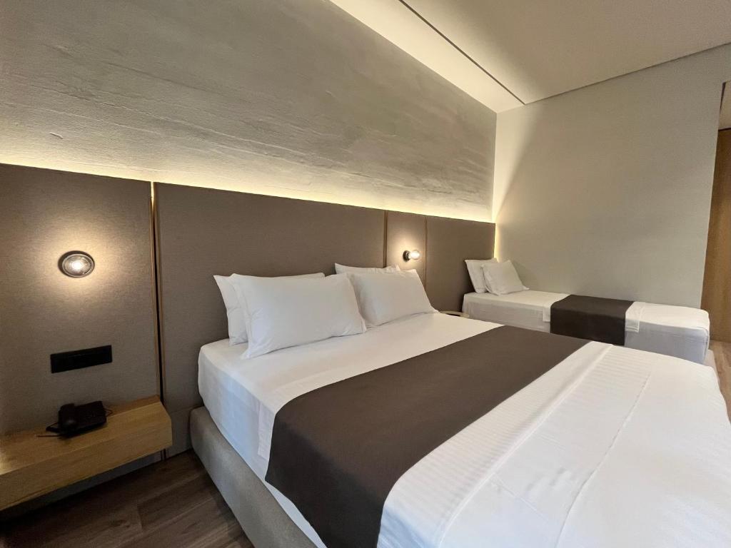 a bedroom with two beds with white and black sheets at Riviera Boutique Hotel by Pomo d'oro in Vlorë