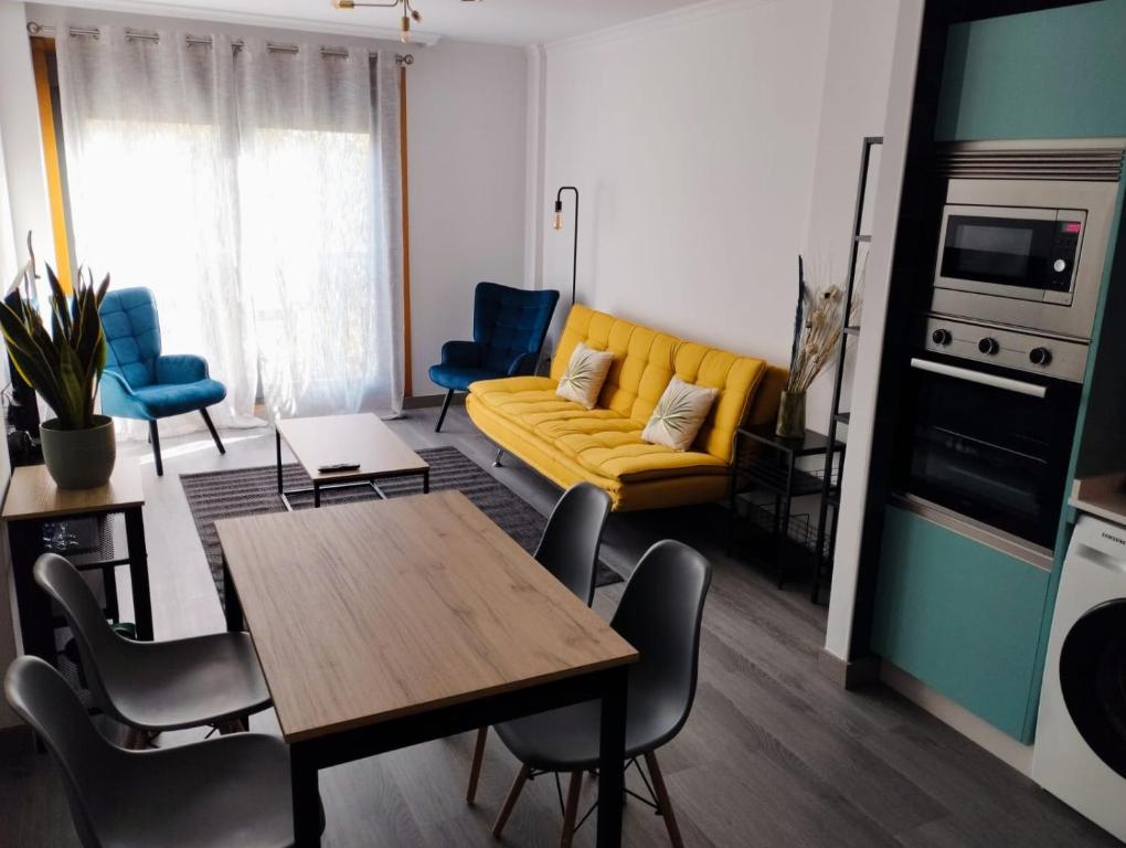 a living room with a yellow couch and blue chairs at Caldasia in Caldas de Reis