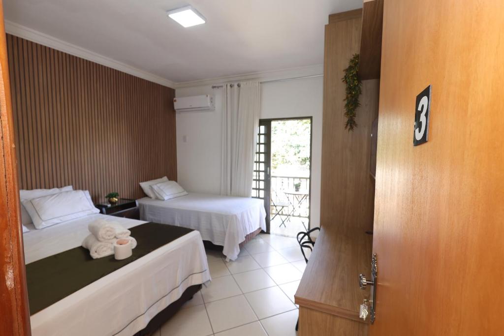 a hotel room with two beds and a window at Pousada House Garden in Goiânia