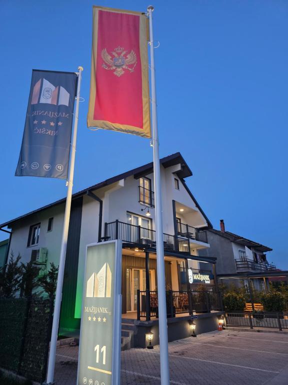 two flags on poles in front of a building at Hotel Mažijanik in Nikšić