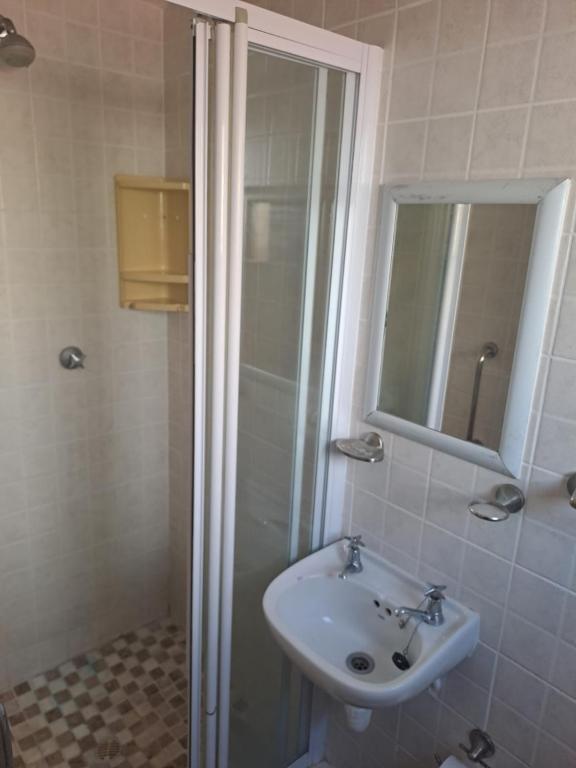 a bathroom with a sink and a shower with a mirror at 65 Rowweklip in Jongensfontein