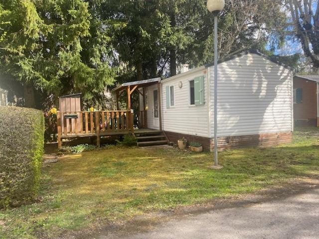 a small white house with a porch and a deck at Mobile home Besse in Besse-et-Saint-Anastaise