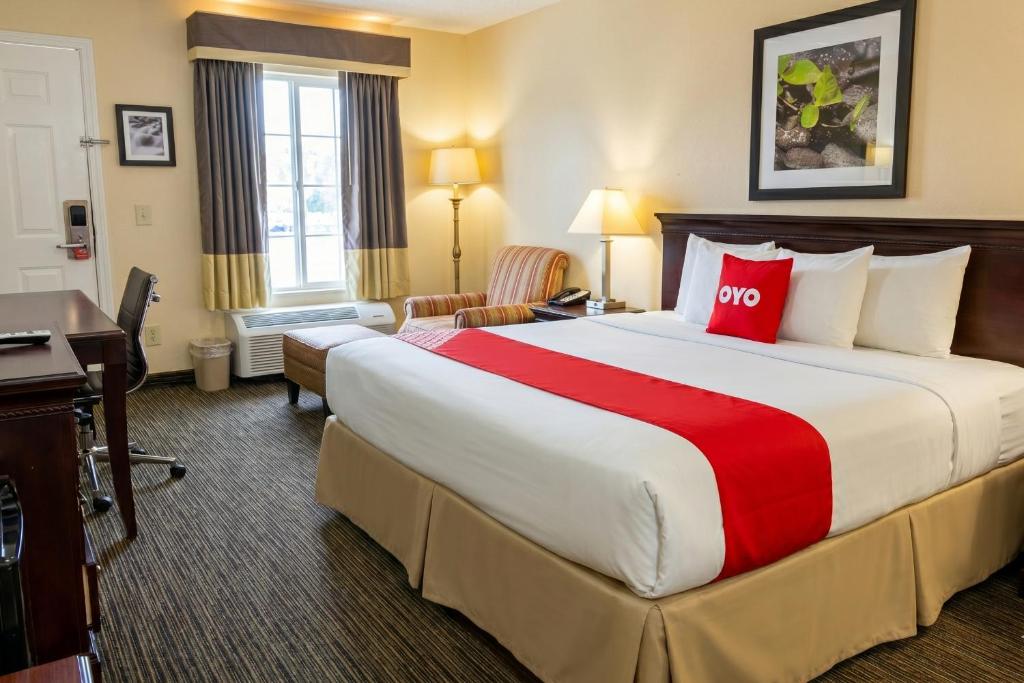 a hotel room with a large bed and a desk at Bonita Lakes Inn by Capital O Meridian I20 in Meridian