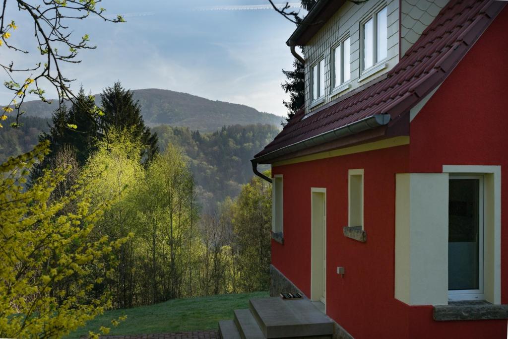 a red house with a view of the mountains at Waldhufenhaus in Schöna in Reinhardtsdorf