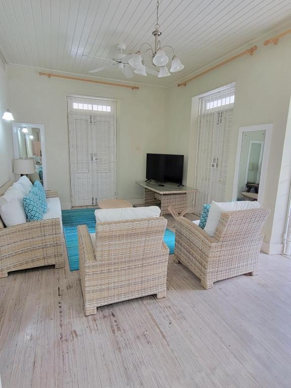 a living room with wicker chairs and a flat screen tv at Clariston in Bridgetown