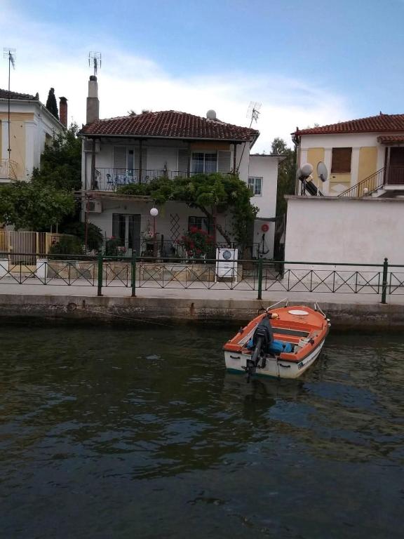 a small boat in the water in front of a house at Athina Studios in Chorto