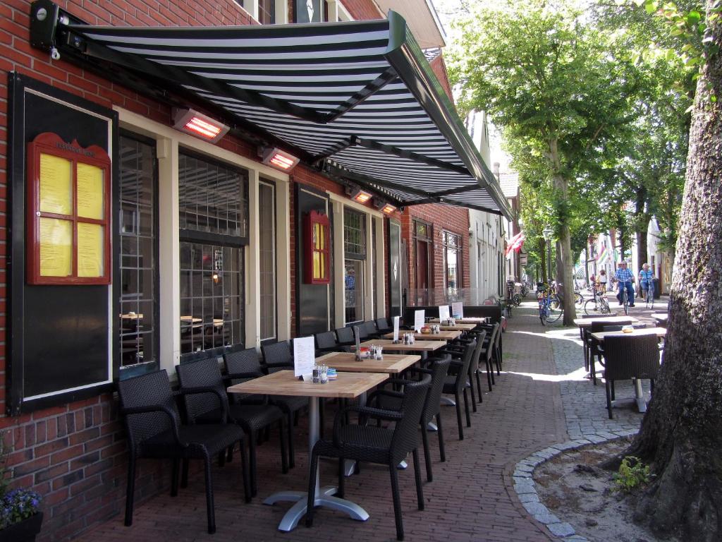 a restaurant with tables, chairs and umbrellas at De Herbergh van Flielant in Oost-Vlieland