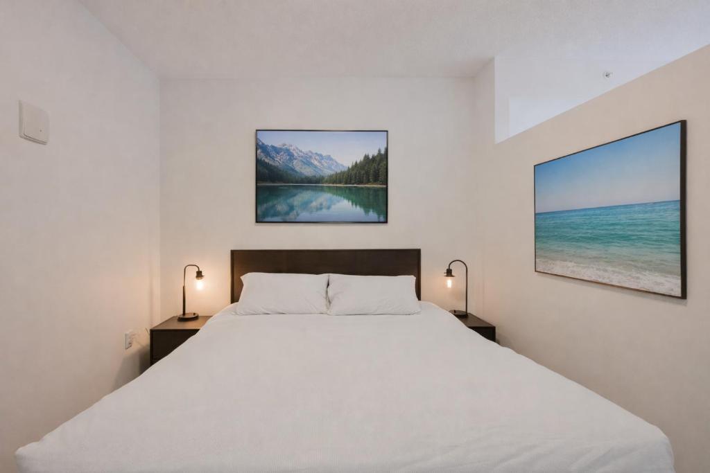 a bedroom with a white bed with two lamps at Chic & Modern Apartment In The Heart Of Downtown in Victoria