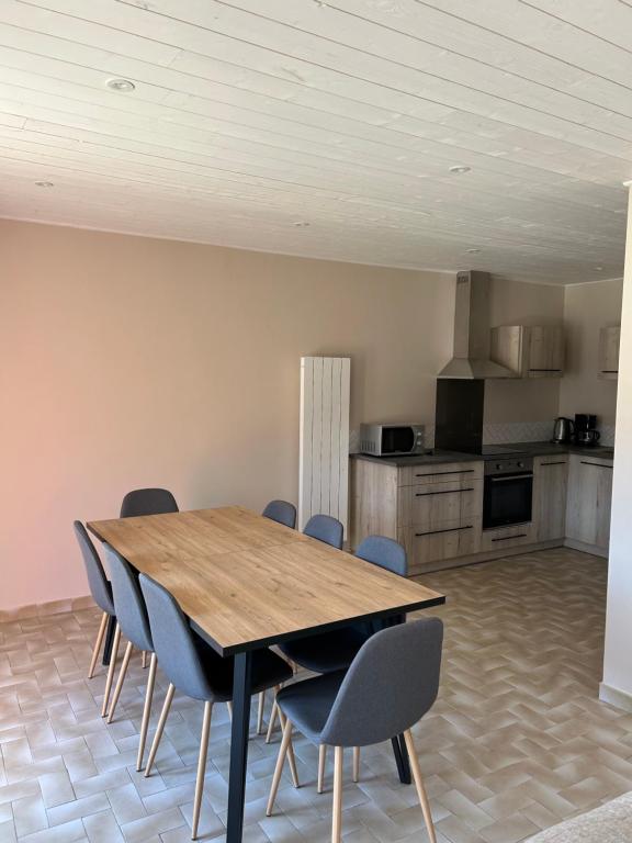a dining room with a wooden table and chairs at Gîte Les Vignes au Cheylard in Le Cheylard