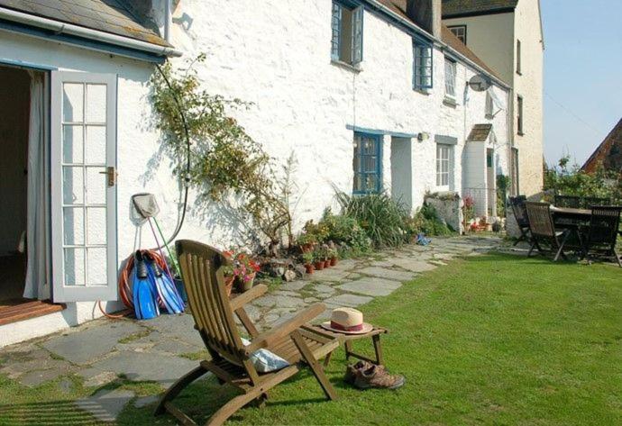 a hat sitting on a chair next to a house at Pebbles in Cadgwith