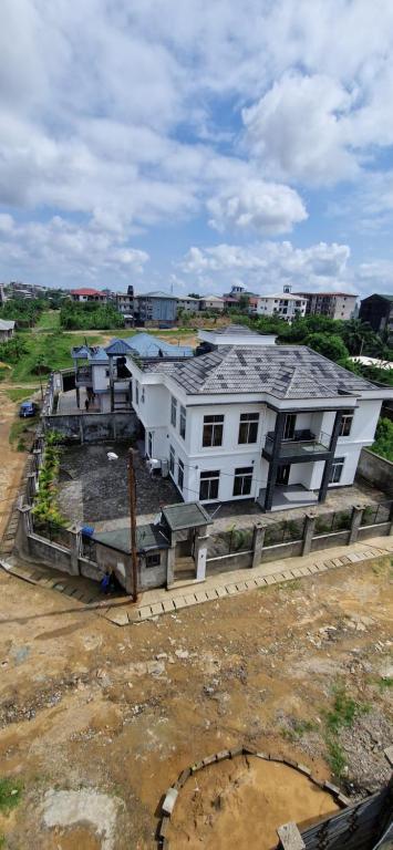 a large white house with a roof on a field at The white house in Douala