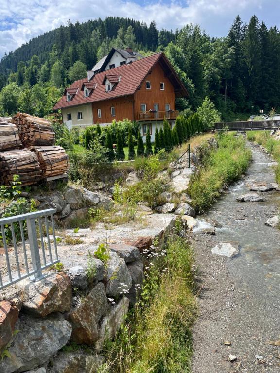 a house next to a river next to a building at Haus Almblick in Gasen