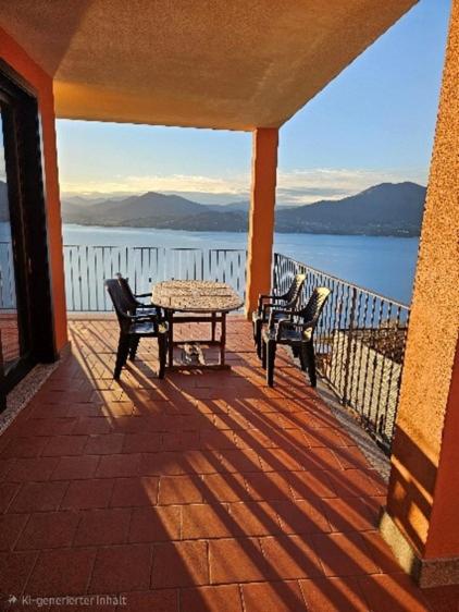 a porch with a table and two chairs and a view of the water at Residence Il Vigneto - Casa Sopralago in Oggebbio