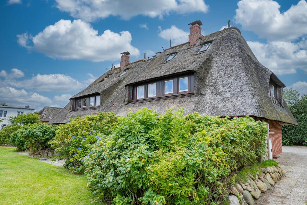 an old stone house with a thatched roof at Wattblick in Braderup