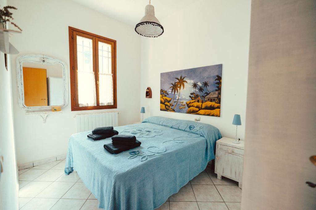 a bedroom with a bed with blue sheets and a painting on the wall at Seaside Beach House with Private Parking in Punta Marina