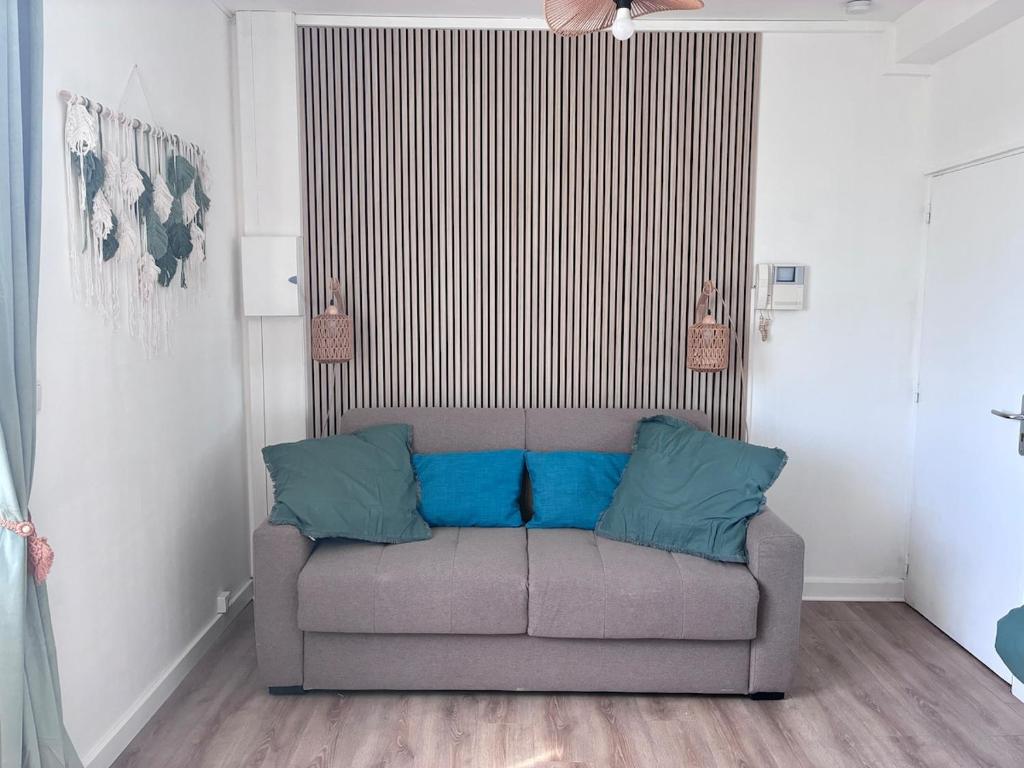 ein Sofa mit blauen Kissen in einem Wohnzimmer in der Unterkunft Studio Aloe in Dunkerque