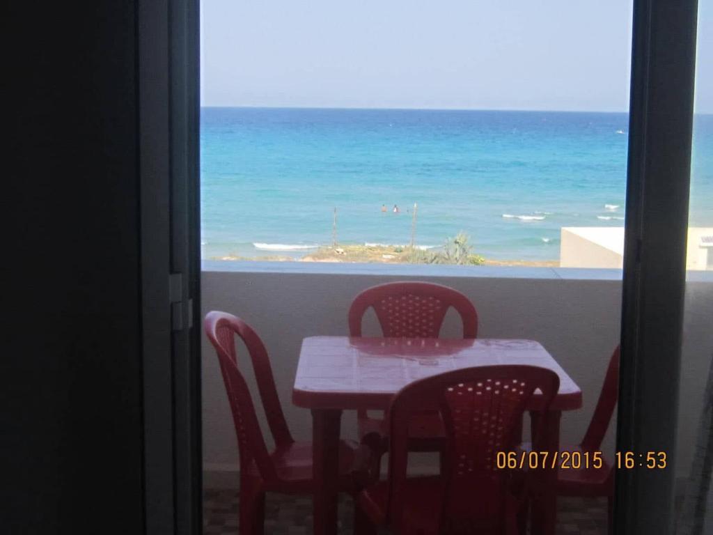 a table and chairs with a view of the ocean at V résidence in Ḩamādat al Kebalou