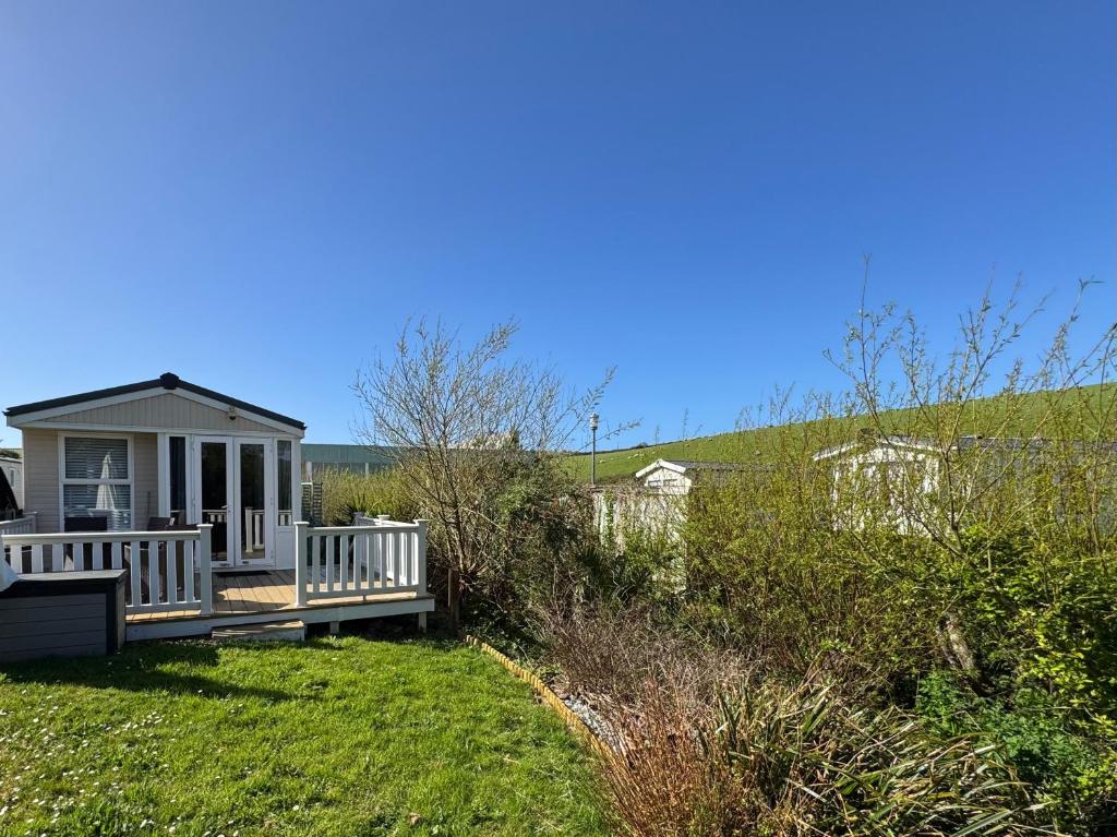 a small house with a porch on a lawn at Bag End, Near Porth Beach, Garden & Stream in Newquay Bay Resort