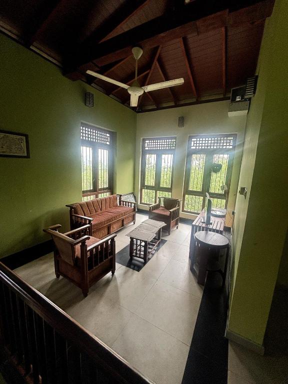 a living room with couches and chairs and windows at Tea Estate Villa in Ratnapura