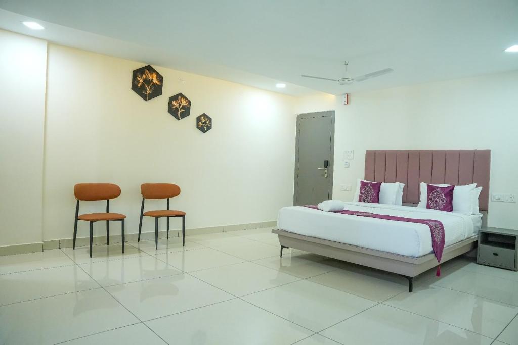 a bedroom with a bed and two chairs at Hotel Flamount Hitech City in Hyderabad
