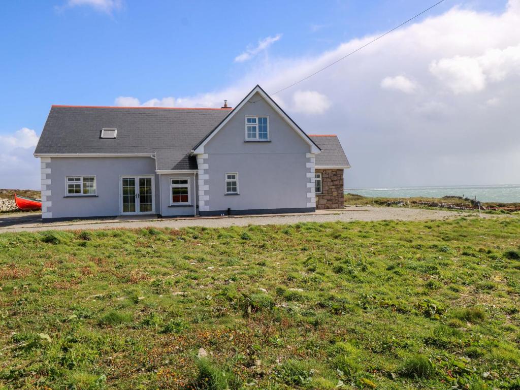 a white house on top of a grassy field at Tí Tom Nárta in Trawbaun