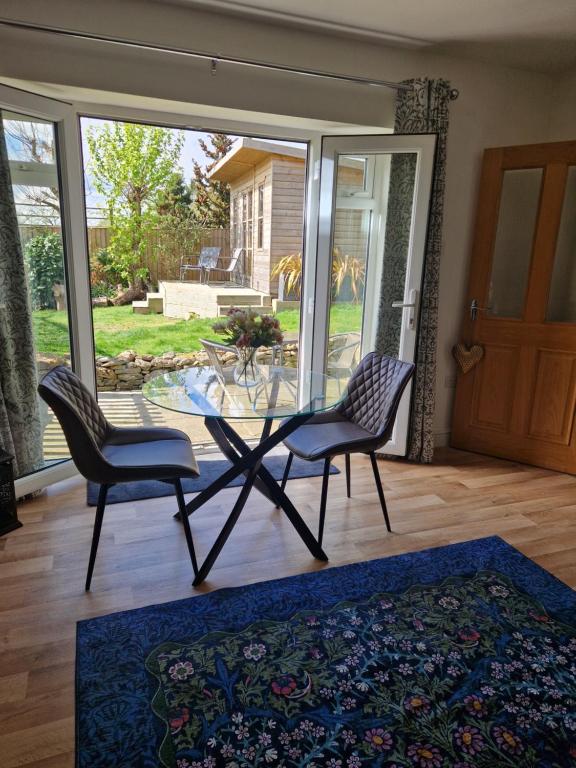 a dining room with a glass table and two chairs at Honeybee Hideaway in Brompton