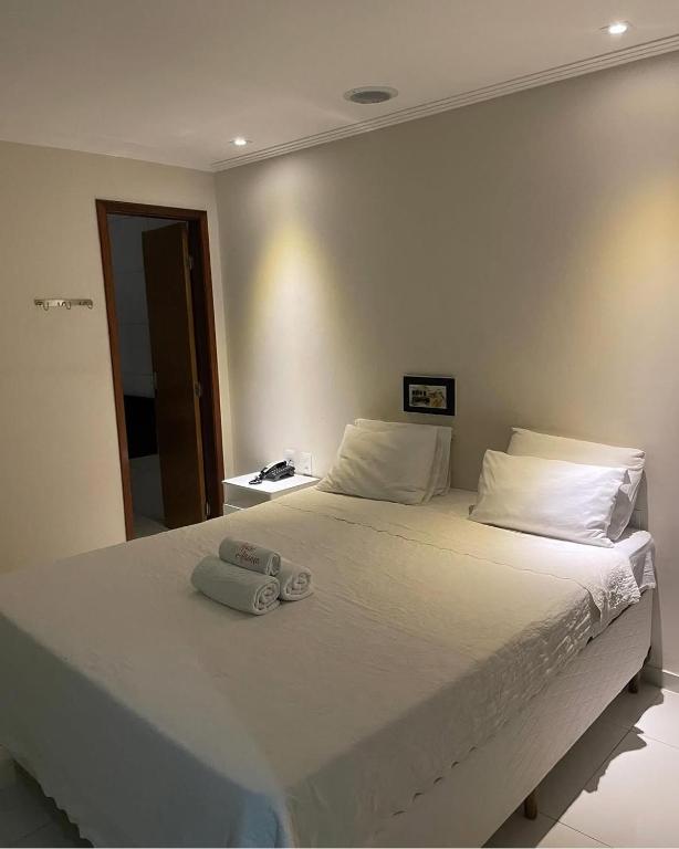 a bedroom with a large white bed with towels on it at Hotel Aliança in Salvador