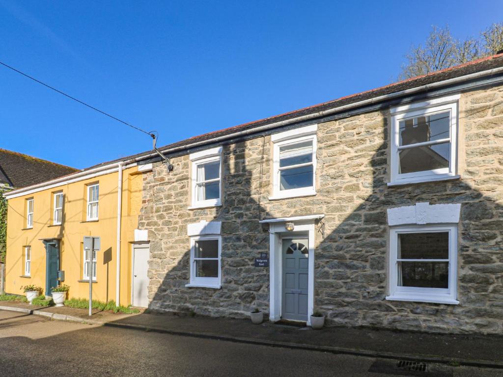 a stone house with white windows and a blue door at Widgeons Keel in Falmouth