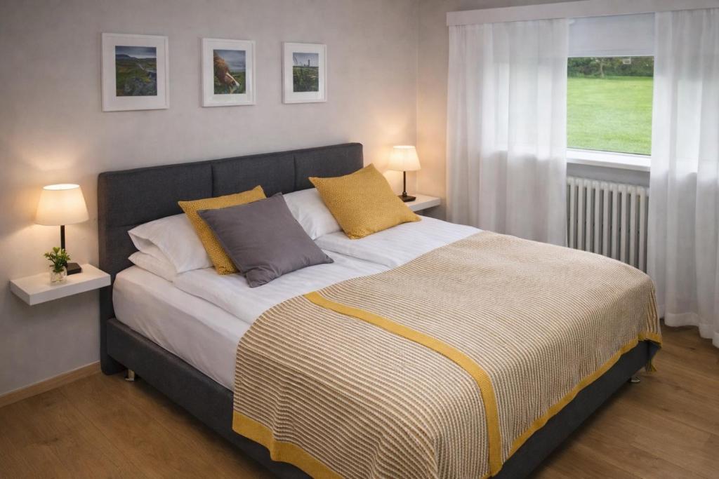 a bed in a bedroom with two lamps and a window at Apartment 19 in Selfoss