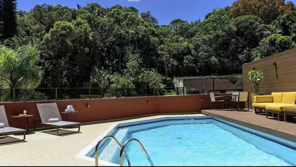 a swimming pool with chairs and a couch and a table at Flat no coração de Joinville in Joinville