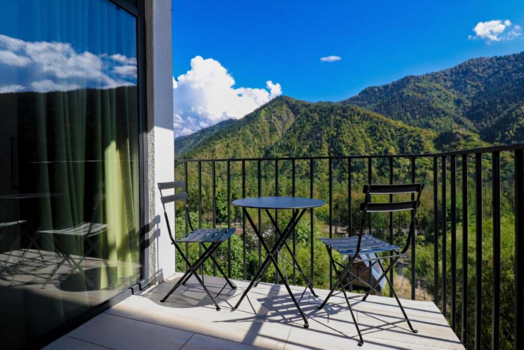 two chairs and a table on a balcony with mountains at Emerald Borjomi Hotel in Borjomi