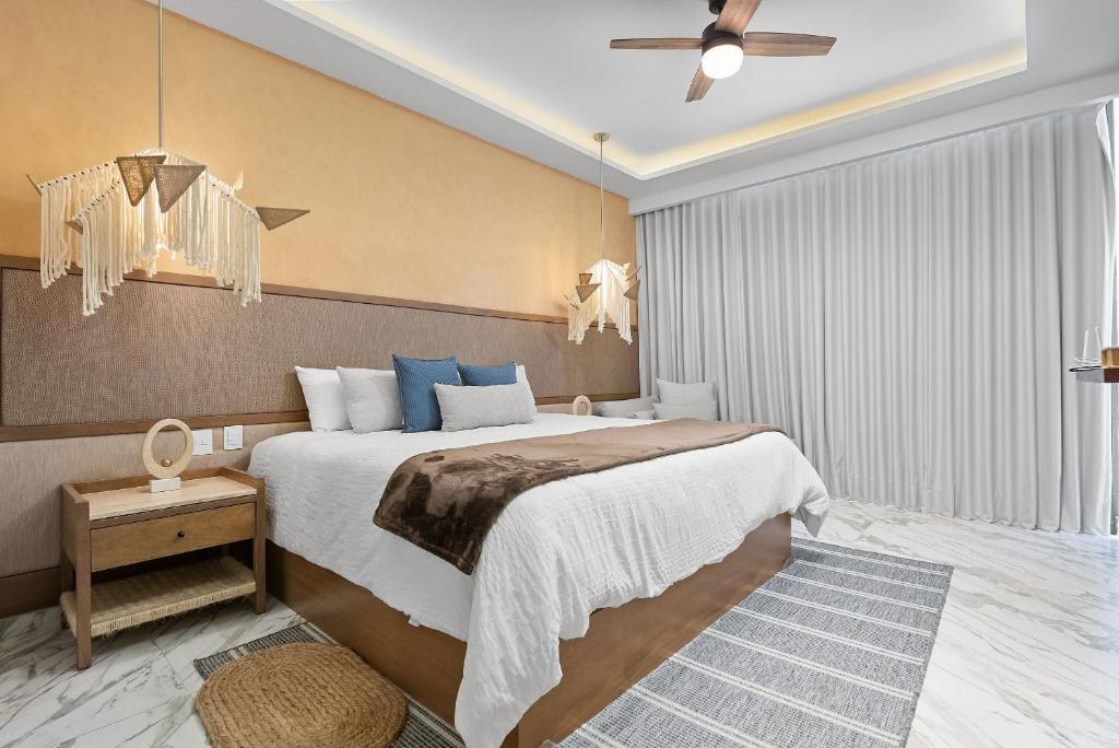 a bedroom with a large bed and a ceiling fan at Bahiban Residences Oceanfront by Monyxbnb in Cruz de Huanacaxtle