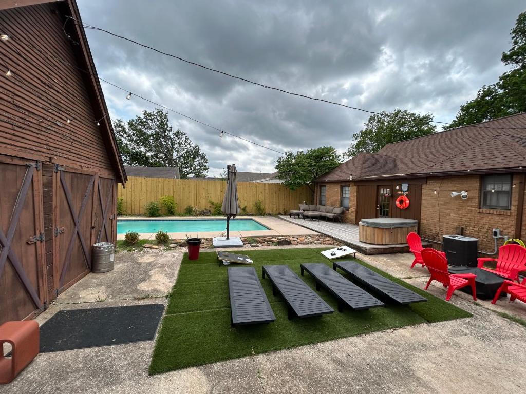 a backyard with a pool and red chairs and a table at In-ground pool, hot tub, fire pit, massage room! in Tulsa